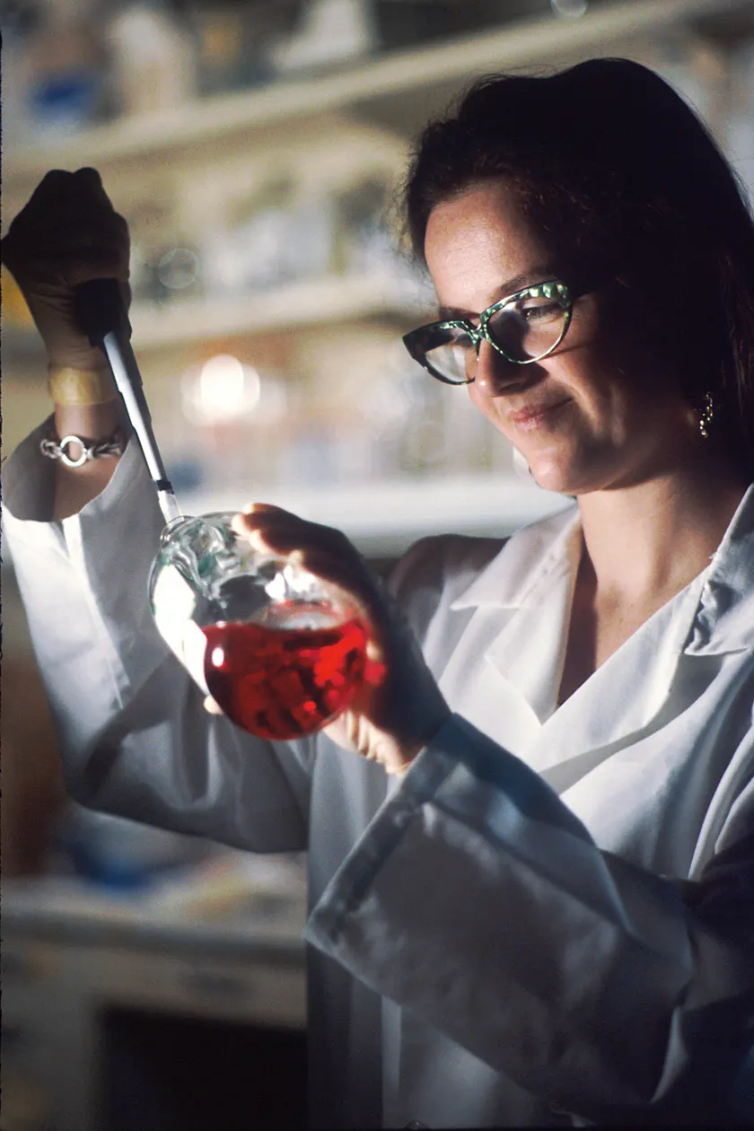 Gloved hands using a pipette to move liquid among small tubes at a laboratory bench