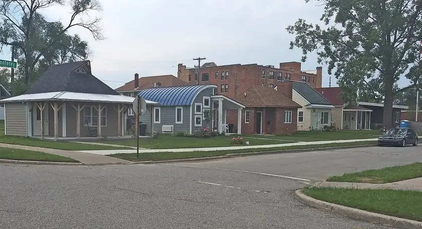 A row of small colorful houses with front porches on a residential street