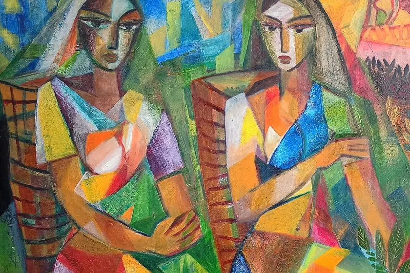 Two women in bright clothes picking tea leaves into baskets on a green hillside
