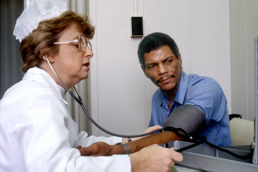 A nurse checking a seated adult patient's blood pressure