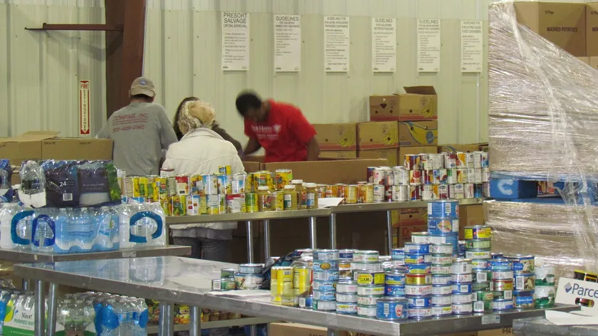Volunteers sorting donated food on tables inside a food bank