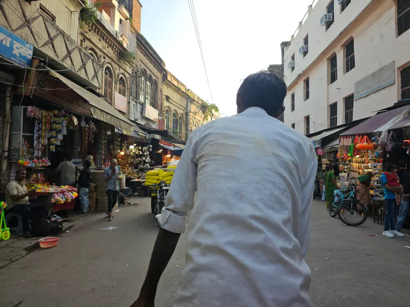 A cycle rickshaw rider seen from behind on a busy street