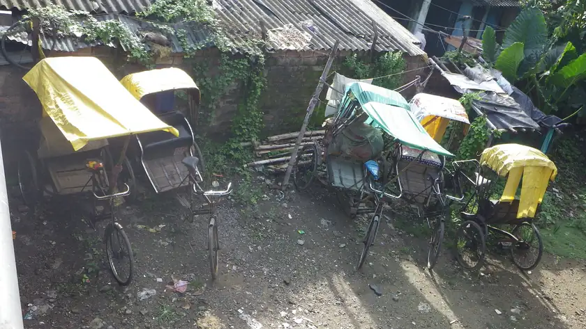 An empty two-seat cycle rickshaw parked on pavement