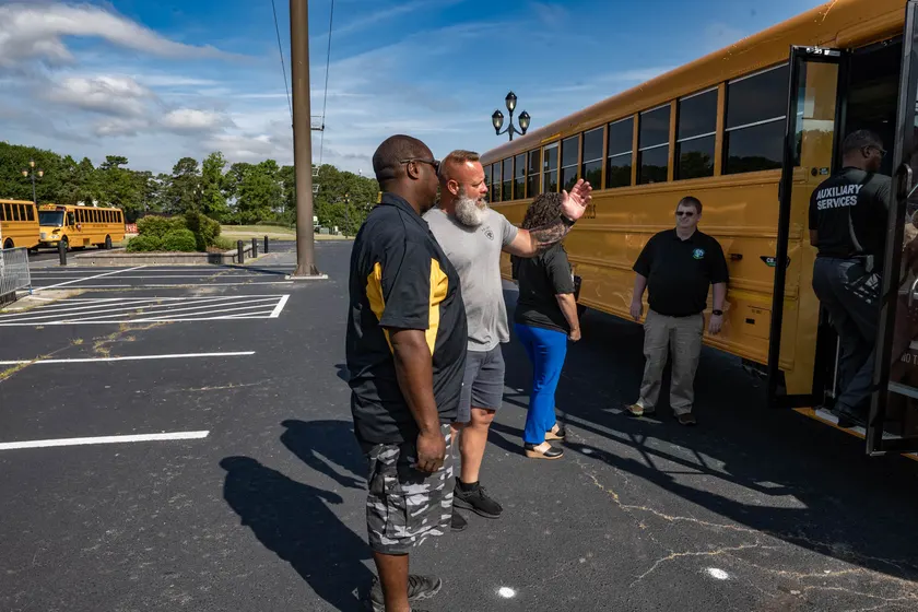 People gathered beside yellow school buses at an outdoor bus-safety event
