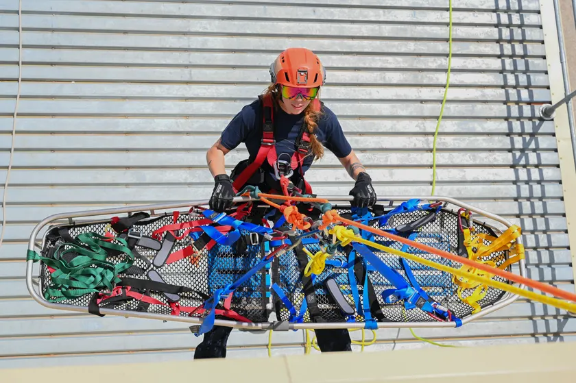 A rescuer in a helmet working with a litter and ropes