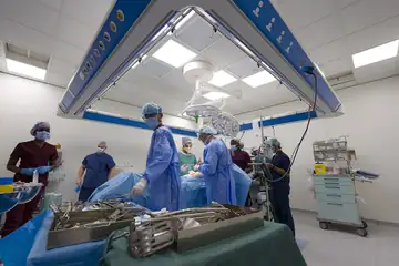 A surgical team in gowns and masks gathered around an operating table