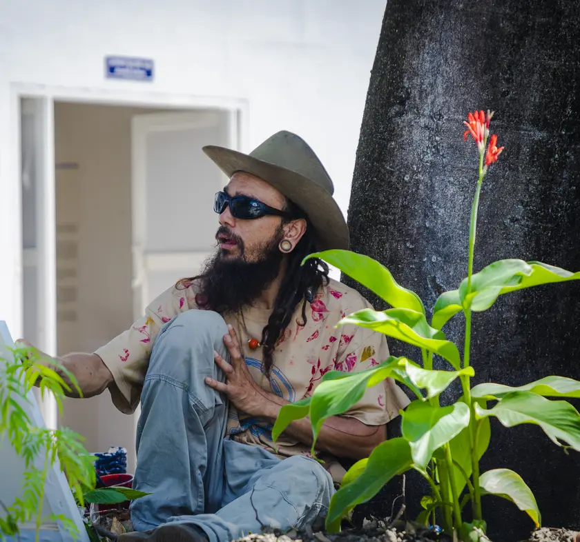 An adult artist sitting outdoors and painting on a canvas