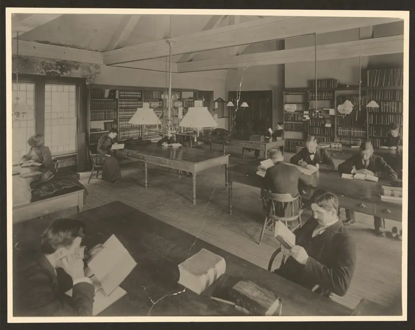 People reading at long tables in a library room