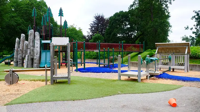 An empty playground with a slide and climbing structure in a park