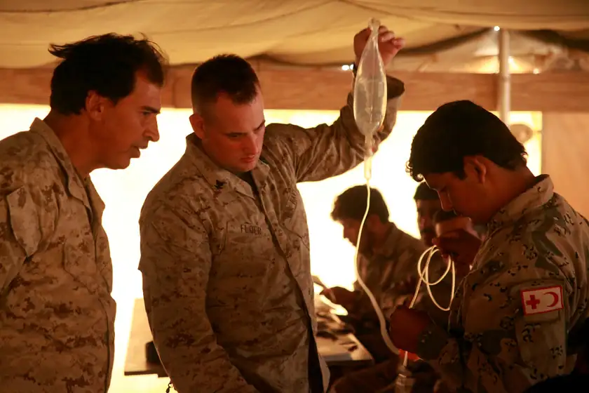 Adults in uniform practicing on a medical training arm