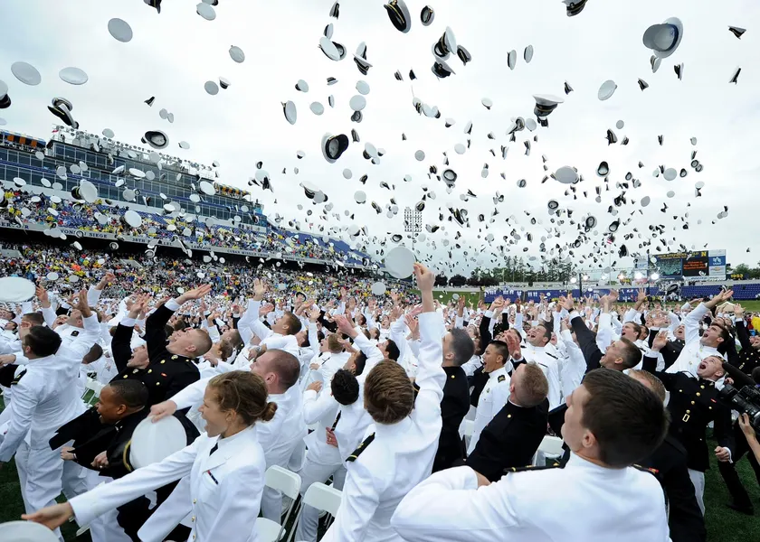 Graduates in uniform throwing their caps into the air