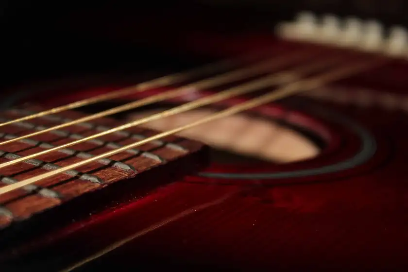 A close-up of the body and strings of an acoustic guitar